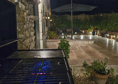 Night time showing seating area with lights, lite patio area and BBQ